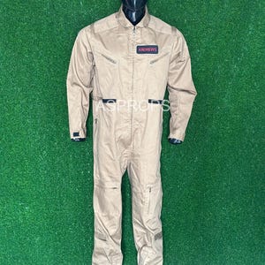 May include: A tan jumpsuit with a zip fastening and multiple pockets. The jumpsuit has a name tag that reads "ANDREWS".