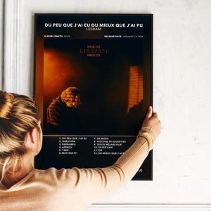 May include: A black framed poster with the text "DU PEU QUE J'AI EU DU MIEUX QUE J'AI PU" and "LESRAM". The poster features a dark image of a person and a list of song titles. Album length is 23-26.