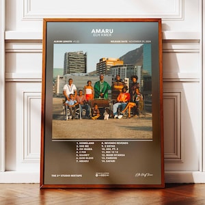 Può includere: Poster incorniciato con la copertina dell'album "Amaru" di Elm Kmer. L'artwork mostra un gruppo di persone in posa su un tetto con una città sullo sfondo. Il poster include il titolo dell'album, la tracklist e la data di uscita.