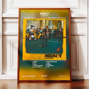 May include: A framed poster for "Mercy" by Laylow. The poster features a photograph of a person standing in a street scene, with the album title and tracklist in a yellow and green gradient design. The release date is December 09, 2016.