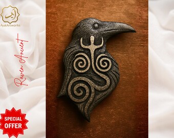 May include: A raven-shaped decorative item with a detailed design. The raven is dark gray with gold-colored accents, featuring a stylized symbol on its chest. The background is a warm brown, and the text "Raven Ancient" is visible.