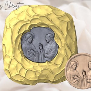May include: A gold-colored, textured frame with a central gray relief depicting two figures. A smaller, circular relief with the same figures is also present. The text "Jesus Christ" is written in cursive at the top.