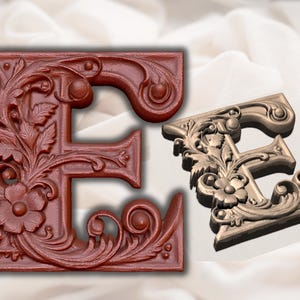 Puede incluir: Una letra E de madera decorativa, adornada y con intrincados detalles florales. La letra está pintada de un color rojo intenso y tiene un diseño tridimensional.