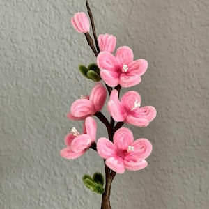 Könnte beinhalten: Eine Blumenarrangement aus rosa Pfeifenputzern in einem braunen Pfeifenputzertopf. Die Blumen sind in Baumform mit grünen Blättern angeordnet.