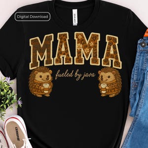 May include: Black t-shirt with the word "MAMA" in a brown, textured font with a floral pattern. Below the word is "fueled by java." Two cartoon hedgehogs holding coffee cups flank the text. "Digital Download" is in the upper left.