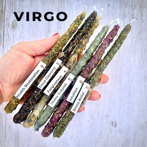 May include: A set of six slender taper candles with textured, herb-infused wax surfaces in shades of green, purple, and cream. Each candle features a small white paper tag with the text Health Restoration, Deep Cleaning, Forgiveness, Divine Support, Intuition, and Stress Relief. The word VIRGO is printed in black at the top.
