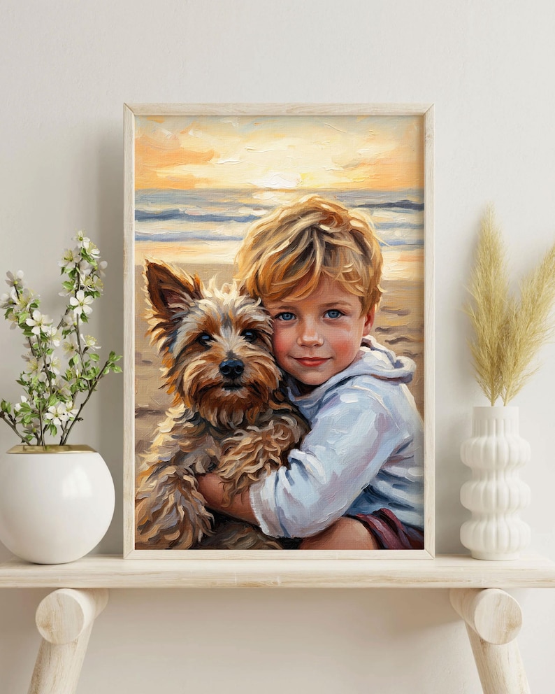 May include: A framed painting shows a child with blonde hair hugging a small, brown and tan dog on a beach at sunset. The artwork has a soft, painterly style, with warm colours dominating the scene. The child is wearing a light blue hoodie.