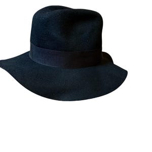 May include: A black fedora hat with a wide brim and a black band around the crown. The hat is made of a soft material and is suitable for various occasions. The hat's brim is approximately 3 inches wide.
