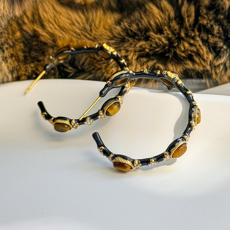 Flat lay of tiger’s eye rhinestone bamboo hoop earrings styled with gold accessories, showing elegant artisan jewelry aesthetic