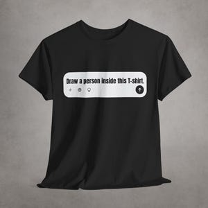 May include: Black t-shirt with white text that says "Draw a person inside this T-shirt." The text is in a white box with a plus sign, a globe, a lightbulb, and an upward arrow.
