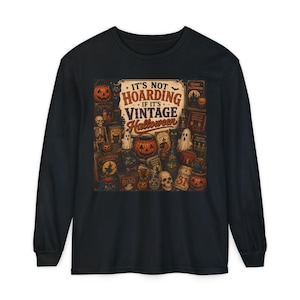 Puede incluir: Una camiseta negra de manga larga con un estampado gráfico central que incluye el texto IT'S NOT HOARDING IF IT'S VINTAGE Halloween. La ilustración muestra varios motivos de Halloween en naranja y marrón, incluyendo calabazas, fantasmas, calaveras y gatos.