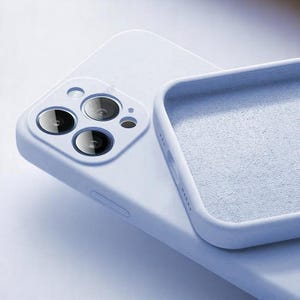 May include: A light blue phone case with a soft, matte finish. The case has a square design with a camera cutout and a textured interior. The phone case is designed to protect the phone from scratches and damage.