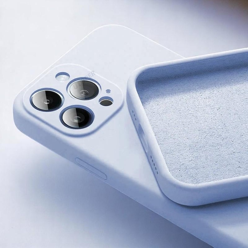 May include: A light blue phone case with a soft, matte finish. The case has a square design with a camera cutout and a textured interior. The phone case is designed to protect the phone from scratches and damage.