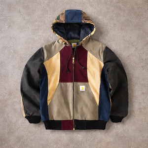 Op de afbeelding: Een veelkleurige jas met capuchon en volledige ritssluiting. De jas heeft panelen van zwarte, bruine, bordeauxrode en blauwe stof. De capuchon heeft een camouflagepatroon met een marineblauw gedeelte. Zwarte geribde zoom en manchetten.