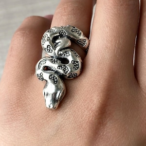 May include: A silver snake ring with a detailed textured design. The snake is coiled and the head is facing forward.