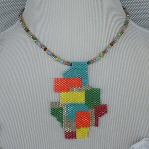 May include: A colorful beaded necklace with a geometric pendant made of small, colorful beads. The pendant is in the shape of a stylized abstract design with red, orange, yellow, green, blue, and silver beads.