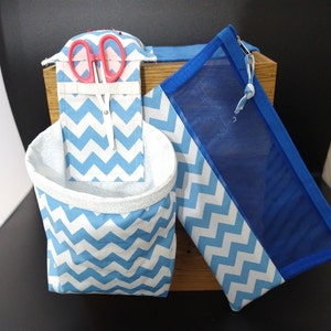 May include: Two blue and white chevron patterned fabric storage bags. One bag is a pouch with a mesh window and the other is a hanging organizer with a pocket for scissors.
