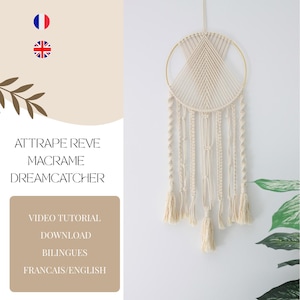Peut inclure: Un attrape-rêves en macramé blanc avec un cercle doré et des glands qui pendent du bas. L'attrape-rêves est suspendu à un mur blanc avec une plante verte en arrière-plan. Le texte "Attrape Reve Macrame Dreamcatcher" est écrit en noir sur un fond beige.