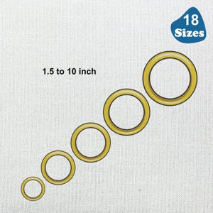 May include: A set of 18 gold-colored metal grommets in various sizes, ranging from 1.5 to 10 inches in diameter.  The grommets are arranged in a line from smallest to largest.