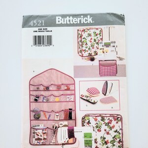 May include: A Butterick sewing pattern with various sewing accessories. The image shows a sewing machine, storage cases, a hanging organiser, and an iron. The pattern cover has the text "4521" and "ONE SIZE".