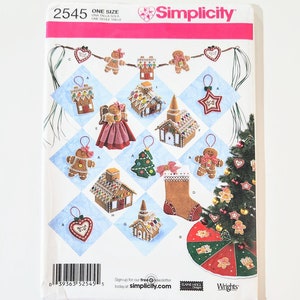 Könnte beinhalten: Simplicity-Schnittmuster 2545 mit verschiedenen Weihnachtsornament-Designs, darunter Lebkuchenhäuser, Lebkuchenmännchen, ein Weihnachtsbaum und ein Strumpf. Das Muster enthält den Text "ONE SIZE" und das Simplicity-Logo.
