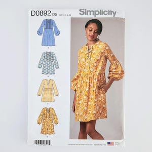May include: Simplicity sewing pattern D0892 D5, sizes U.S. 4-12, featuring four dress designs. The dress on the right is a yellow floral print with long sleeves and a lace-up neckline. The pattern includes dress variations with different sleeve and neckline styles.