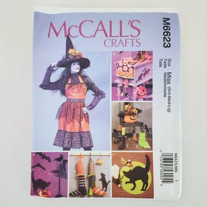 May include: A McCall's Crafts sewing pattern, M6623, featuring Halloween-themed craft projects. The cover displays a witch costume and various decorative items, including a black cat silhouette and pumpkin decor. The pattern size is Miss (Sml-Med-Lrg).