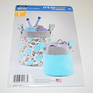 May include: A sewing pattern package featuring two fabric storage baskets. The larger basket has a floral pattern with blue and brown accents, while the smaller one is solid blue. The package includes the text "IT'S SO EASY" and "W0187".