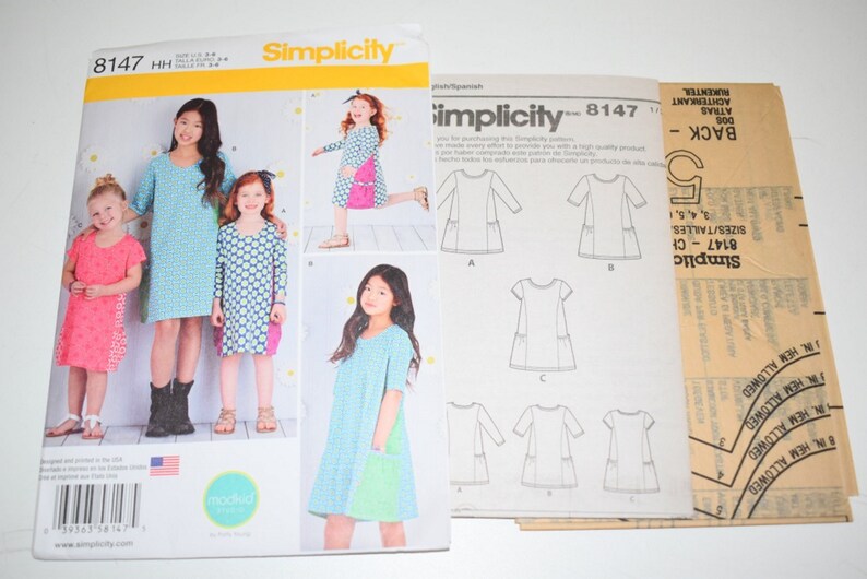 May include: Simplicity sewing pattern 8147 for girls' dresses. The pattern envelope features images of the finished dresses in various colors and patterns. Includes pattern pieces and instructions for different dress styles.