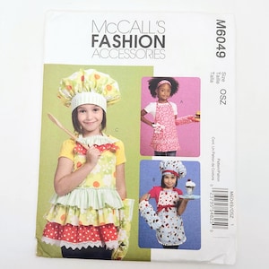 May include: McCall's Fashion Accessories sewing pattern M6049. The pattern features images of children wearing aprons and chef hats. The pattern includes the size OSZ. The cover is white with colorful images.