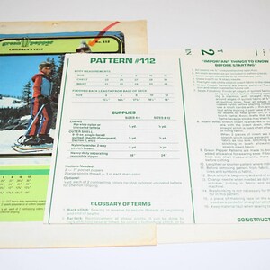 May include: Vintage Green Pepper Children's Wear pattern #112. The pattern includes instructions and measurements for sizes 4-12. The cover features a child in a red, blue, and white ski suit on a snowy mountain.