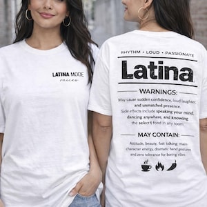 May include: Two women wearing white t-shirts with the word "Latina" printed on the back. The front of the shirt has the text "LATINA MODE raices". The back of the shirt also has the words "RHYTHM LOUD PASSIONATE" and a list of warnings and may contain items.