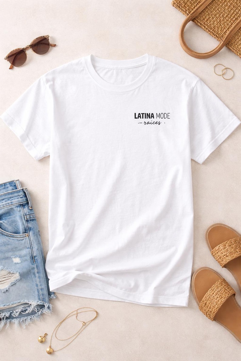 May include: A white t-shirt with the text "LATINA MODE - raices" printed in black. The shirt is displayed with denim shorts, sunglasses, sandals, a handbag, and jewellery.