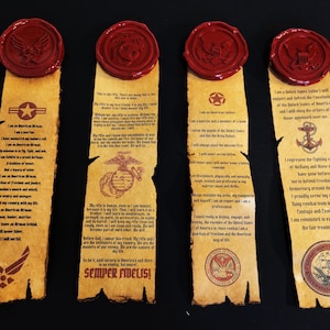 May include: Four vertical parchment-style scrolls featuring printed text and military emblems for the Air Force, Marine Corps, Army, and Navy. Each scroll is topped with a circular red wax seal and features weathered, burnt-look edges.