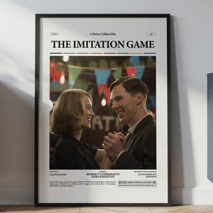 May include: Framed movie poster for "The Imitation Game" featuring actors. The poster has a black frame and is displayed against a white wall. The image shows a couple holding hands, with the movie title at the top.