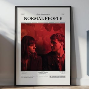 Puede incluir: Un póster enmarcado de la serie "Normal People" con dos personas en una imagen de tonos rojos. El póster está en un marco negro y está apoyado contra una pared blanca. El póster se exhibe en una habitación con muebles.