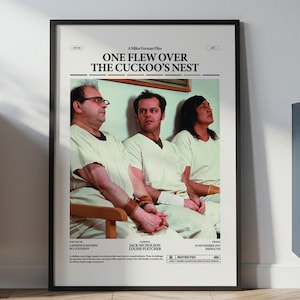 May include: A framed poster for the film "One Flew Over the Cuckoo's Nest" with three figures in white attire. The poster, in a black frame, is displayed on a wall. The room has a wooden floor and a cabinet.