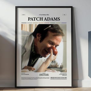 Könnte beinhalten: Gerahmtes Filmplakat für "Patch Adams" mit Robin Williams und einer roten Clownsnase. Das Poster hat einen schwarzen Rahmen und wird vor einer weißen Wand präsentiert. Im Hintergrund befinden sich ein Schrank und dekorative Gegenstände.