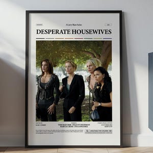 Puede incluir: Un póster enmarcado de la serie de televisión "Desperate Housewives". El póster, en un marco negro, muestra a cuatro mujeres frente a un fondo borroso al aire libre. El título del programa está en la parte superior.