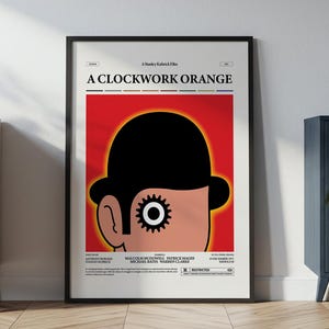 May include: Framed poster of "A Clockwork Orange" film. The artwork depicts a character's face with a black bowler hat against a red backdrop. The poster is in a black frame and is leaning against a white wall. The poster is in a black frame.