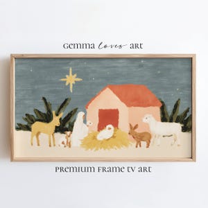 Puede incluir: Una impresión enmarcada de un pesebre. La obra de arte representa una estrella, un establo con techo rojo y figuras de animales y personas en una paleta de colores apagados. El texto "Gemma Loves Art" y "Premium Frame TV Art" son visibles.