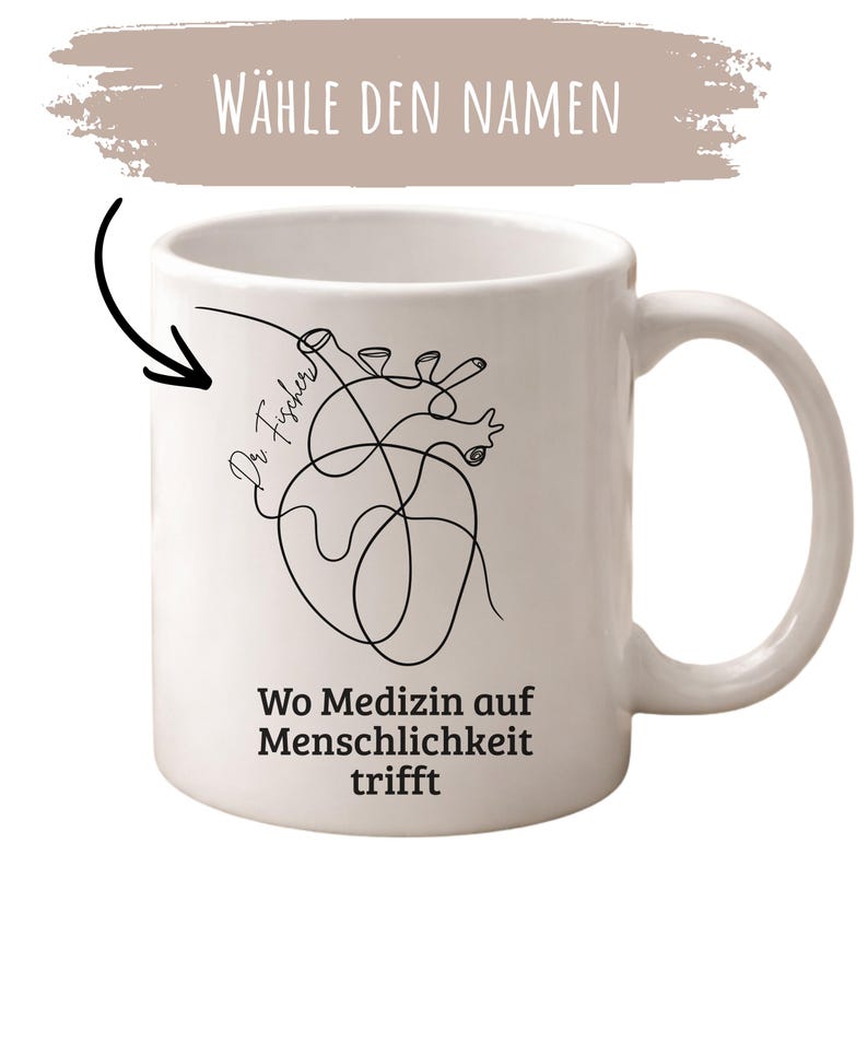 May include: White ceramic mug with a black line art illustration of a heart. The mug has the text "Wo Medizin auf Menschlichkeit trifft" and "Dr. Fischer" with the words "W&auml;hle den Namen" above the mug.