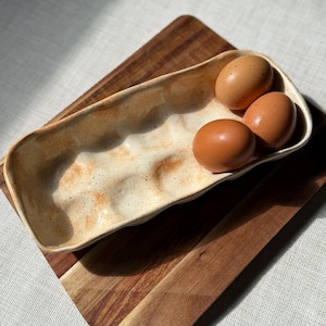 May include: A set of three ceramic nesting bowls with a speckled, cream-colored exterior and a dark brown interior. The bowls vary in size, with the largest measuring approximately 6 inches in diameter.