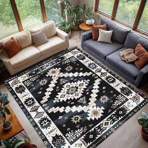 May include: A large, rectangular area rug with a geometric pattern in black, white, and tan. The rug features a central design with star and diamond shapes, bordered by a repeating pattern. The rug is placed in a living room with two sofas and large windows.