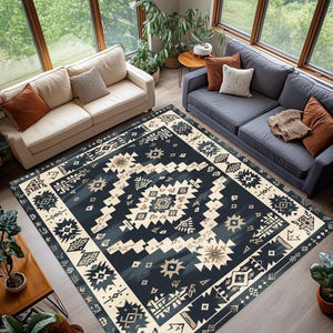 May include: A large, rectangular area rug with a geometric pattern in navy blue, cream, and tan. The rug features a central design of diamonds and starbursts, framed by a border of repeating shapes. The rug is placed in a living room setting.