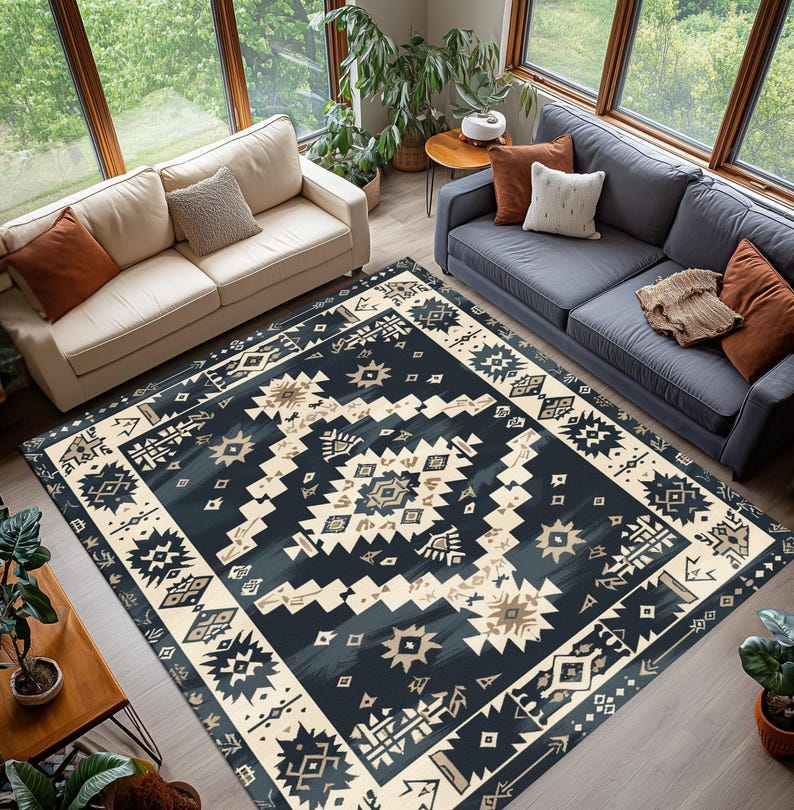 May include: A large, rectangular area rug with a geometric pattern in navy blue, cream, and tan. The rug features a central design of diamonds and starbursts, framed by a border of repeating shapes. The rug is placed in a living room setting.