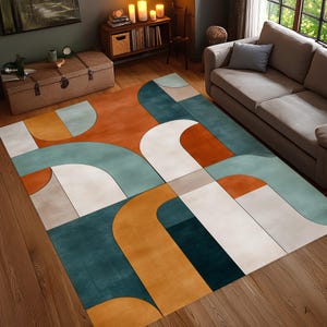 May include: A large area rug with a geometric design in shades of teal, orange, white, and beige. The rug features curved and rectangular shapes, creating a modern and abstract pattern. The rug is placed on a wooden floor.