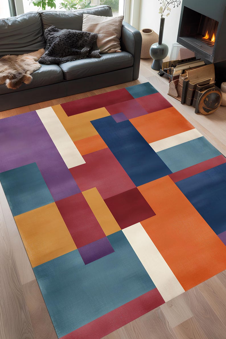 May include: A colorful geometric area rug with a modern design. The rug features a pattern of overlapping rectangles in shades of blue, orange, red, purple, and white. The rug is placed on a hardwood floor in a living room setting.