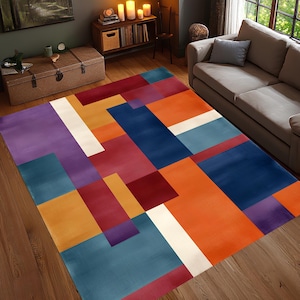 May include: A rectangular area rug with a geometric pattern. The rug features blocks of color in shades of purple, orange, blue, red, and white. The rug is placed on a hardwood floor in a living room setting.