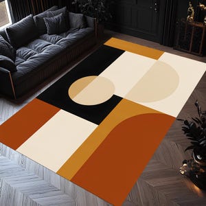 May include: Geometric area rug featuring a modern design with a black, cream, orange, and tan color palette. The rug has a large rectangular shape with abstract shapes and a circular design. The rug is placed on a wooden floor.